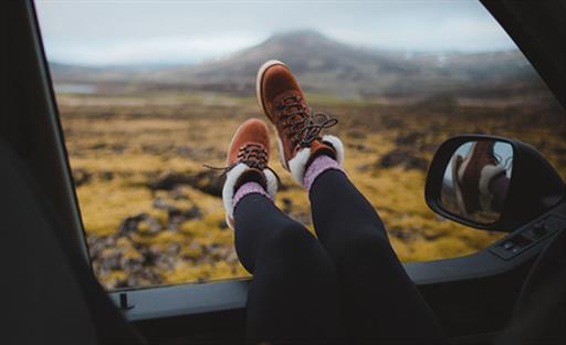 Feet hanging out of car window with nature in the background