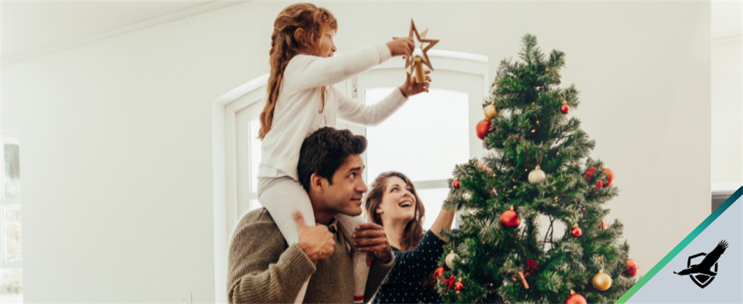 Young couple's daughter placing star on top of Christmas tree